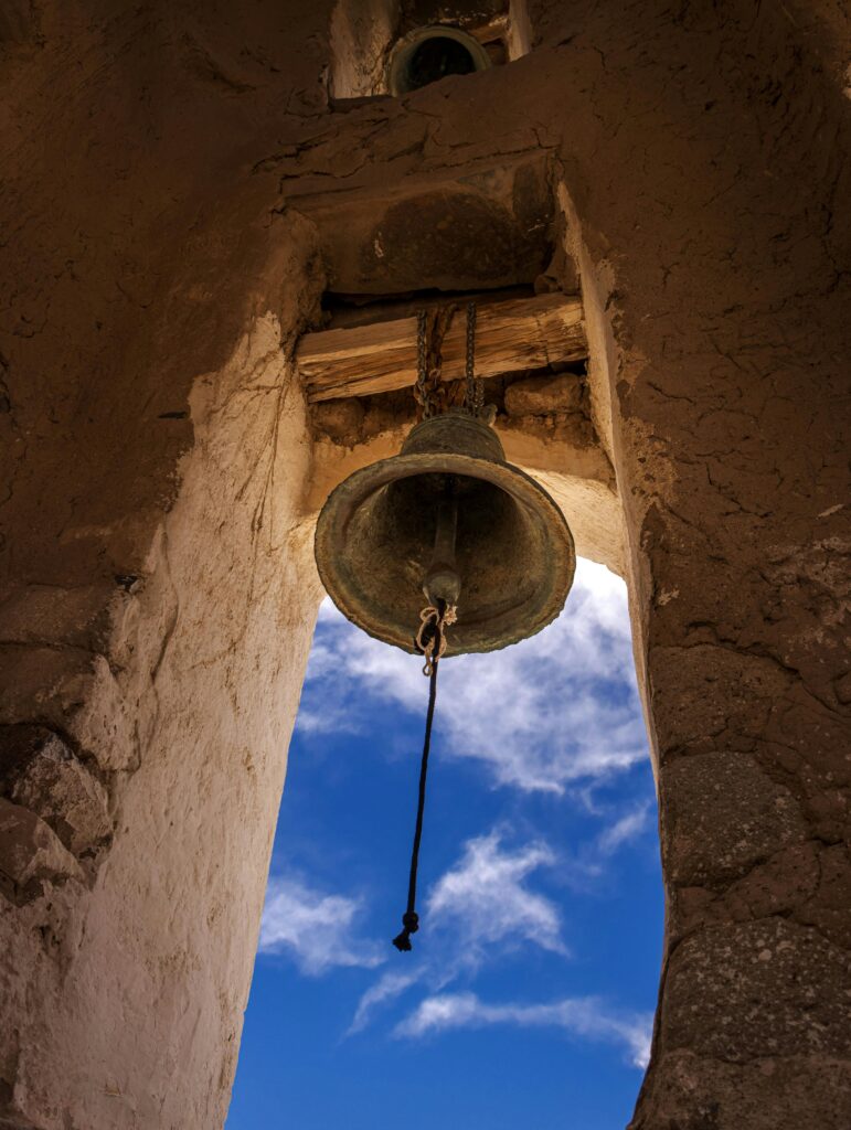 bell mounted in stone structure with blue sky seen behind